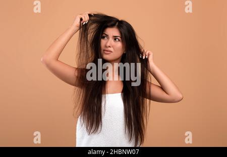 Femme arménienne frustrée montrant ses longues serrures endommagées, ayant les mauvais cheveux jour, bouleversé par son désordre cheveux Banque D'Images