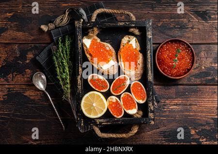 Toasts et tartelettes avec caviar rouge et beurre dans plateau en bois fond en bois.Vue de dessus Banque D'Images
