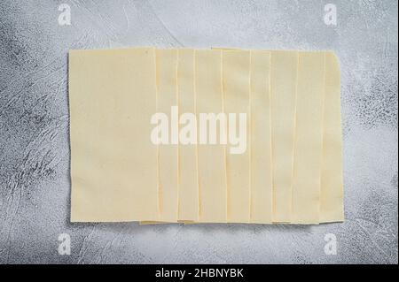 Des feuilles de lasagne crues sont empilées sur une table de cuisine. Arrière-plan blanc. Vue de dessus Banque D'Images