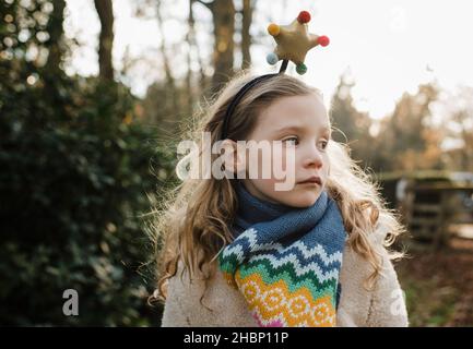 fille avec l'étoile de noël sur sa tête tandis que dehors dans le soleil d'or Banque D'Images