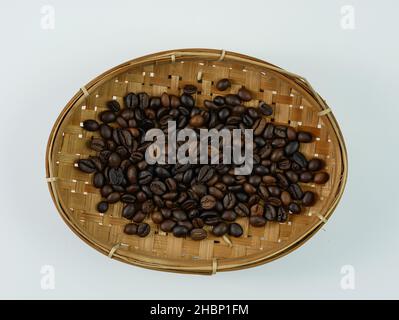 Grains de café de qualité dans un panier en bambou isolé sur fond blanc Banque D'Images