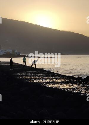 Les gens qui marchent le long de la promenade au coucher du soleil Banque D'Images