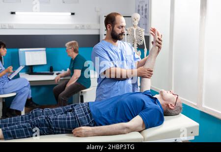 Chiroptractor faisant un massage ostéopathique sur un patient âgé pour la récupération du muscle de la main.Infirmière qui aide à étirer l'articulation du bras de l'homme âgé pour le traitement de l'ostéopathie et les soins de santé. Banque D'Images