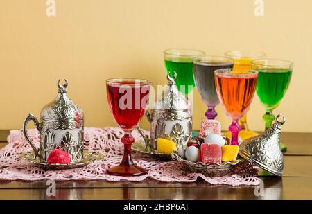 Liqueur traditionnelle de rose rouge turque dans un élégant verre de liqueur sur une table en bois avec café et bonbons Banque D'Images