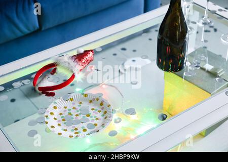 Table avec décor et bouteille de champagne vide dans la chambre après la fête de Noël Banque D'Images