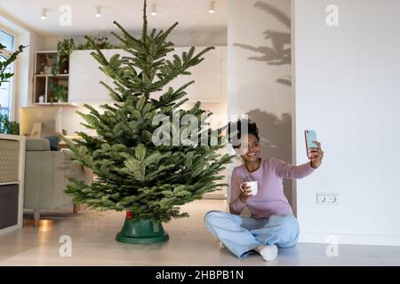 Bonne femme prendre photo selfie avec arbre de noël naturel jouir de la beauté naturelle et de la fraîcheur du pin Banque D'Images