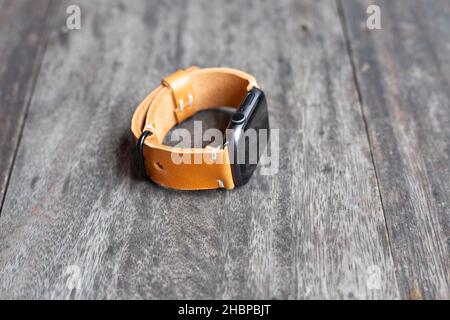 Bracelet de montre marron clair en cuir marron clair travail artisanal sur le bois Banque D'Images