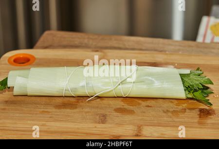 Un bouquet de légumes verts prêt à l'emploi se trouve sur une planche en bois dans la cuisine, pour un plat de vinaigrette Banque D'Images