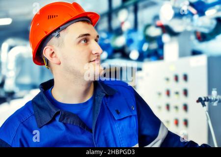 L'opérateur de la chaudière à gaz contrôle la pression sur l'équipement.Portrait d'un ingénieur en casque au travail.Flux de travail authentique. Homme travaillant dans la chaufferie.Arrière-plan flou.Gazéification et énergie.Arrière-plan. Banque D'Images