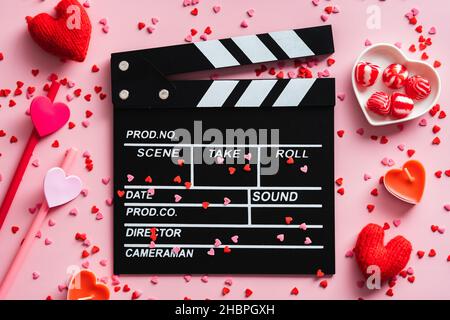 Tableau à motif de clapper et décorations de la Saint-Valentin sur table rose.Vue de dessus. Banque D'Images