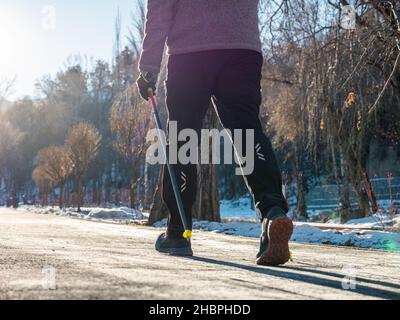 Jambes d'un homme, marche nordique en hiver.Loisirs fitness et mode de vie sain en plein air dans la nature.Motivation et paysage d'hiver inspirant. Banque D'Images