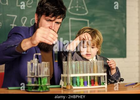 Programme scolaire.Garçon d'école mignon enfant expérimentant avec des liquides.Tubes à essai pour enseignants et enfants.Leçon scolaire.La persévérance paye Banque D'Images