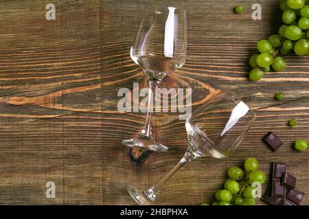 Verres de vin et raisins mûrs isolés sur une table en bois Banque D'Images