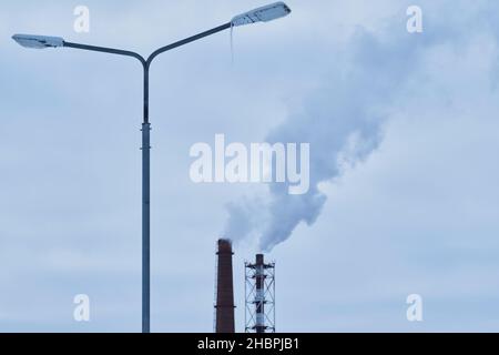 Lampe de rue avec glace congelée sur fond deux conduites de charbon de puissance industrielle fumeur.concept d'énergie et de chauffage en hiver Banque D'Images