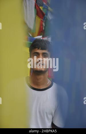 Foyer sélectif d'un jeune indien regardant la caméra tout en se tenant autour des drapeaux de prière bouddhistes Banque D'Images