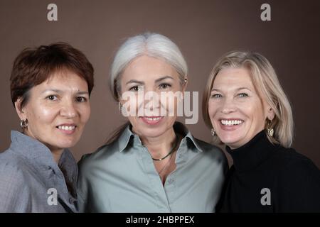 Portrait de belles femmes mûres souriant à l'appareil photo isolé sur fond gris Banque D'Images