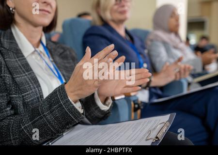 Une jeune déléguée féminine et ses collègues étrangers se claquant la main à l'orateur après une présentation ou un rapport à la conférence Banque D'Images