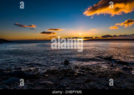 Coucher de soleil derrière les nuages au-dessus de la baie de Mount's depuis Trevean Cove près de Penzance, Cornwall, Royaume-Uni Banque D'Images