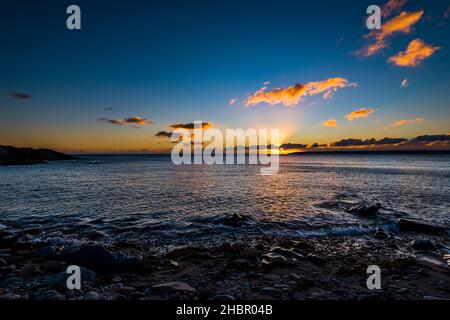 Le soleil se couche derrière les nuages au-dessus de la baie de Mount's depuis Trevean Cove près de Penzance, Cornwall, Royaume-Uni Banque D'Images