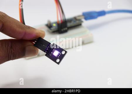 Module de LED ARGB tenu à la main connecté au micro-contrôleur en arrière-plan, module de LED avec des voyants lumineux Banque D'Images