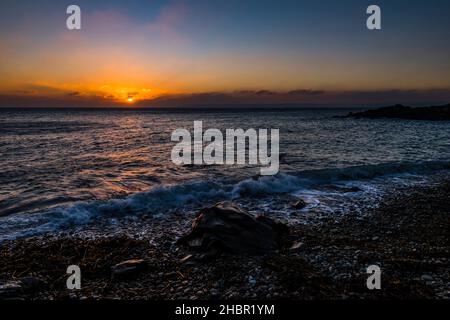 Coucher de soleil à travers les nuages au-dessus de la baie de Mount's depuis Trevean Cove près de Penzance, Cornwall, Royaume-Uni Banque D'Images