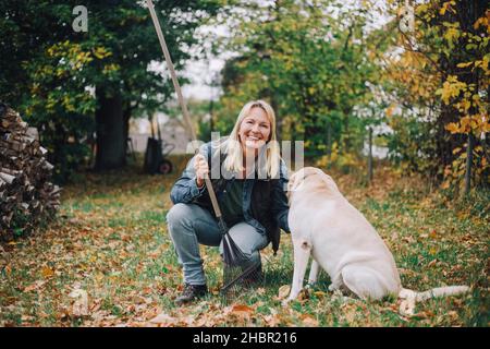 Portrait d'une femme souriante avec un chien dans l'arrière-cour Banque D'Images