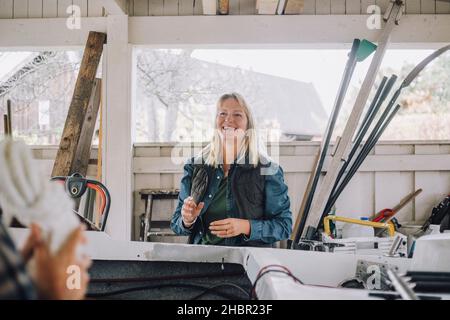 Femme souriante parlant avec un ami masculin dans un garage Banque D'Images