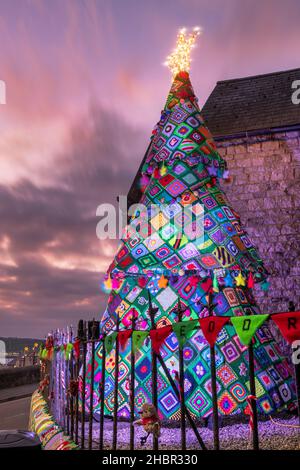 Appledore, North Devon, Royaume-Uni.21st décembre 2021.Le jour du solstice d'hiver, Un arbre de Noël géant tricoté et crocheté illumine le jour le plus court de l'année à Appledore, dans le nord du Devon.Les bénévoles ont passé de nombreuses heures à crocher suffisamment de carrés pour produire l'incroyable exposition qui comprend une chaise, des bas de Noël, le chat endormi, des pompons robins, le GUI et l'arbre géant de 4,5 mètres.Crédit : Terry Mathews/Alay Live News Banque D'Images