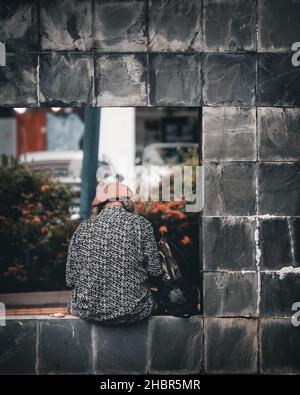 SINGAPOUR, SINGAPOUR - 13 novembre 2021 : cliché vertical d'une personne âgée assise seule dans la rue Toa Payoh, Singapour Banque D'Images