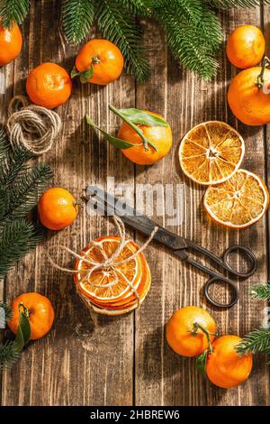 En-cas de tranches d'oranges sèches.Agrumes séchés pour les décorations de Noël.Tangerines avec feuilles, branches de sapin, ciseaux et fil.Filet de bois Banque D'Images