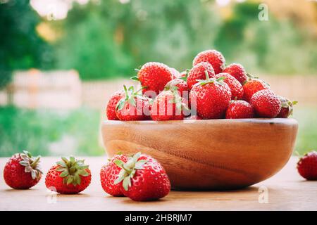 Bol en bois rempli de fraises rouges mûres fraîches sur une table en bois Banque D'Images