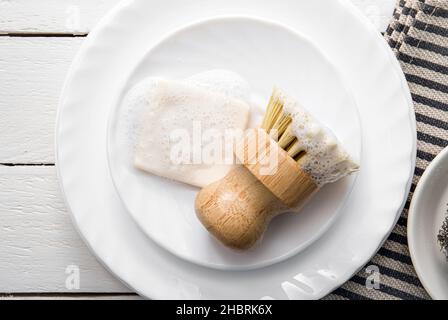 Savon à vaisselle solide, recouvert de mousse.Un style de vie sans gaspillage.Savon lave-vaisselle sur pile de plaques avec brosse en sisal mousseuse pour la cuisine. Banque D'Images