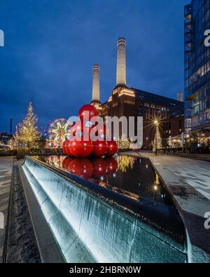 Des arbres de Noël, une roue de ferris et des boules rouges géantes dans la fontaine du Winter Village près de la centrale électrique Battersea à Londres. Banque D'Images