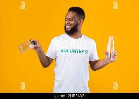 Homme noir volontaire choisir entre bouteille en verre, fond jaune Banque D'Images