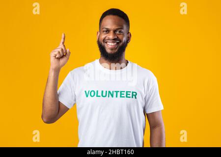 Un volontaire afro-américain qui pointe le doigt vers le haut sur fond jaune Banque D'Images