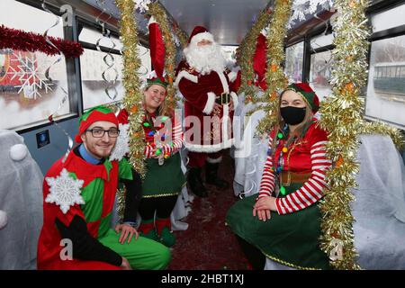 Ayr, Ayrshire, Écosse : les bus Stagecoach Santa viennent en ville par un bus Stagecoach à la gare routière d'Ayr. Le bus ouvert a été aménagé comme une grotte.Le véhicule a été transformé en un pays merveilleux pour l’hiver pour un week-end seulement avec le Père Noël et ses elfes qui ont mis en place une grotte de fortune, et dans le processus de collecte de £185 dons pour la charité des enfants, le bus sensoriel d’Aoife.Dans la grotte gratuite socialement distancée du dépôt d'Ayr Stagecoach, les enfants ont dit à Santa ce qu'ils veulent pour Noël avant de recevoir un cadeau.Père Noël avec ses elfes elfes Banque D'Images