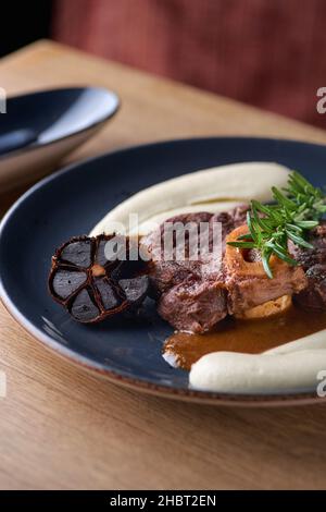 Osso buco, tige de veau cuite.Ossobuco avec purée de légumes-racines et ail noir Banque D'Images