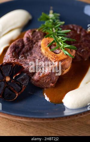 Osso buco, tige de veau cuite.Ossobuco avec purée de légumes-racines et ail noir Banque D'Images