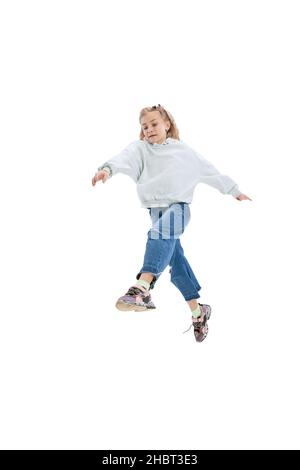 Portrait dynamique de petite fille, enfant dans des vêtements décontractés sautant, ayant l'amusement isolé sur fond gris studio. Banque D'Images