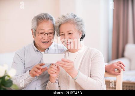 Couple âgé utilisant un smartphone à la maison Banque D'Images