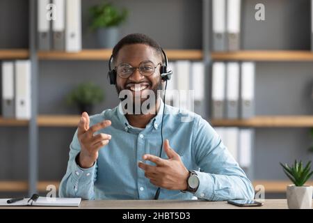 Souriant sympathique jeune afro-américain barbu gars dans les lunettes et les gestes de casque et regarde la caméra Banque D'Images