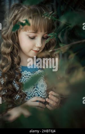 fille de 9-12 ans - avec l'apparence d'une princesse aux cheveux longs, dans un épais d'hortensias. une belle fille regarde les fleurs. Banque D'Images