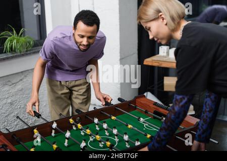 manager afro-américain jouant au baby-foot avec un collègue blond flou Banque D'Images