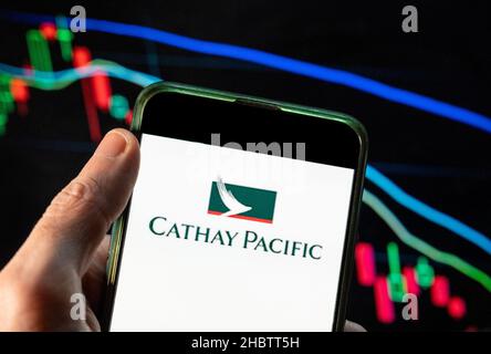 Chine.09th décembre 2021.Sur cette photo, le logo Cathay Pacific Airway de la compagnie aérienne de Hong Kong est affiché sur un smartphone avec un graphique d'indice boursier économique en arrière-plan.Crédit : SOPA Images Limited/Alamy Live News Banque D'Images