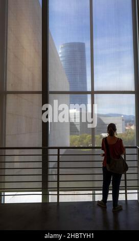 Bilbao, pays basque, Espagne.Septembre 2017.Une jeune fille regarde à travers une grande fenêtre à l'intérieur du Musée Guggenheim d'art contemporain de Bilbao Banque D'Images