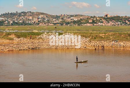 Antananarivo, Madagascar - 07 mai 2019: Personnes travaillant près de la rivière le jour ensoleillé - pêche, faire de la lessive, faire des briques pour les maisons, les maisons à la colline dans Banque D'Images