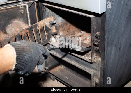 Nettoyage de la chaudière à combustible solide des restes de bois de chauffage et de charbon.Chaudière avec amortisseur ouvert.Efficacité de chauffage dans la maison. Banque D'Images