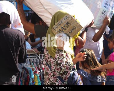 Manille, Philippines.21st décembre 2021.Un vendeur musulman a été vu couvrir son visage d'un écriteau, pendant la séance de shopping.alors que les acheteurs commencent à affluer vers cette destination populaire pour les fêtes à venir, à la recherche des meilleures offres de Noël,Le ministère de la Santé (DOH) a rappelé aux vacanciers de faire preuve de prudence car le risque d'infection par le virus corona (Covid-19) est élevé dans les zones surpeuplées.Crédit : SOPA Images Limited/Alamy Live News Banque D'Images