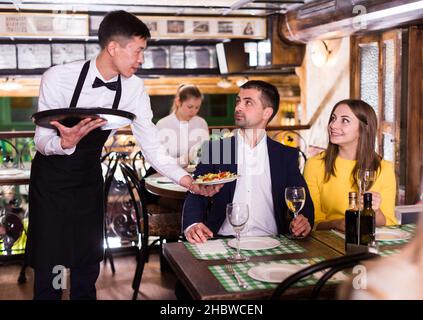 Homme serveur est apporte ordre à couple qui ont le dîner et boire du vin Banque D'Images