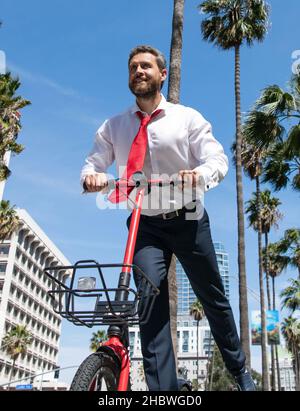 Un homme d'affaires heureux a plaisir à se faire une petite arnaque le long de la rue de la ville, e-scooter Banque D'Images